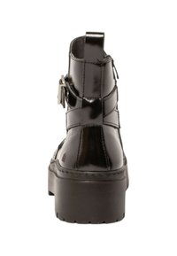 Botas de tobillo de charol negro con suela gruesa, detalle de correa y tirador en la parte posterior. Textura suave y diseño minimalista.