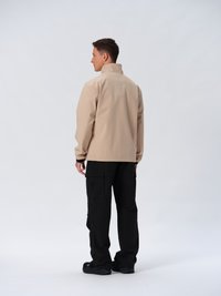 Beige vattentålig jacka med ståkrage, parat med svarta cargo-byxor med sidofickor och robusta svarta skor.