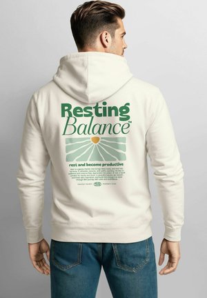 Cremfarbener Hoodie mit einem großen grünen Grafikdruck auf dem Rücken, auf dem "Resting Balance" und Text zu sehen sind. Verfügt über eine Kängurutasche und eine Kapuze mit Kordelzug.