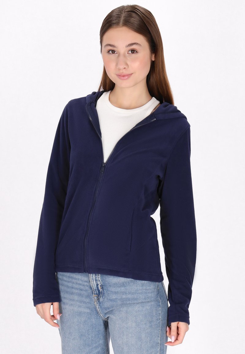 Giacca a zip in pile blu navy con cappuccio, dotata di maniche lunghe e una texture liscia. Indossata sopra una maglietta bianca semplice e jeans azzurri chiari.