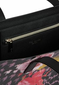 Interno di una borsa in tessuto nero con una tasca con cerniera dorata, caratterizzata da una stampa floreale sull'esterno nei toni del rosa, giallo e nero.