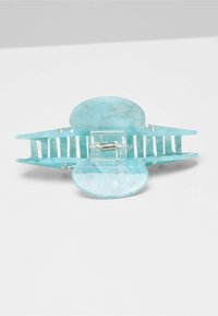 Turquoise hair claw clip made of glossy acrylic with a marbled texture, featuring an internal spring and multiple grip teeth for secure hold.