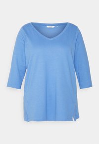 Tunic blu chiaro con scollo a V, maniche a tre quarti, tasche laterali e vestibilità comoda. Realizzata in tessuto morbido e traspirante.