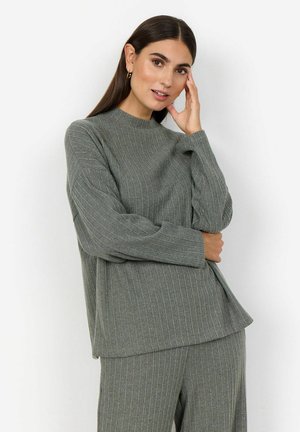 Maglione a coste di un verde chiaro, con collo alto e maniche lunghe. Il tessuto ha una consistenza morbida e una vestibilità comoda, abbinato a pantaloni coordinati.