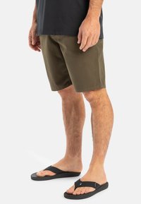 Olive green shorts with a straight cut, made from cotton, paired with black flip-flops featuring a textured strap and flat sole.