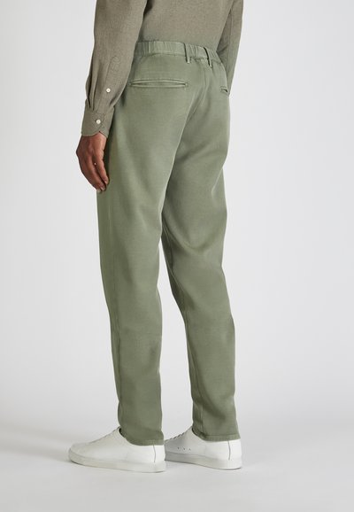 Lichtgroene tapered broek met een zachte textuur, elastische tailleband en twee achterzakken. Gekocht in combinatie met witte sneakers.