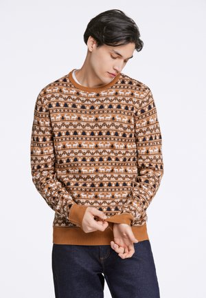 Suéter marrón con un patrón navideño de renos blancos y árboles negros, con puños y dobladillo acanalados. Fabricado en tela de punto.