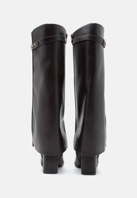 Czarne skórzane kozaki do kolan o gładkim wykończeniu, kwadratowych obcasach, bocznych zamkach błyskawicznych oraz regulowanym pasku akcentowanym metalowym detalem.