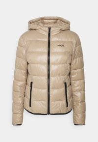 Beżowa kurtka puchowa z kapturem, z poziomymi pikowanymi sekcjami, czarnym zapięciem na zamek i bocznymi kieszeniami. Logo HUGO w kolorze czarnym.