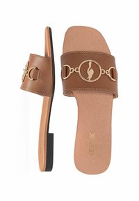 Brązowe klapki z szerokim paskiem i złotym okrągłym zapięciem. Podeszwa jest płaska z teksturowaną wkładką.