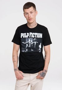 Sort bomulds T-shirt med grafisk tryk fra "Pulp Fiction" med hvid tekst og sort-hvide billeder af to karakterer.