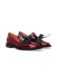 Rode lakleren schoenen met een glanzende afwerking, een platte zwarte zool en een prominente zwarte strikaccent aan de voorkant.