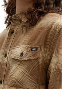 Bruine en beige geruite flanellen shirt met knoopsluiting, een borstzak en een zwart Vans logo label op de zak. Gelaagd stof.