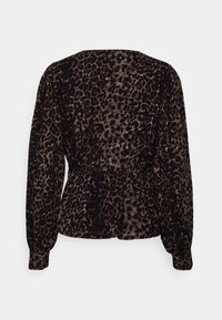 Blouse à manches longues avec imprimé léopard marron et noir, taille cintrée et manches boutonnées, vue de dos sur fond uni.
