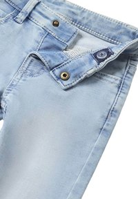 Jeans in denim blu chiaro con chiusura a zip e bottone, cuciture visibili e dettagli in metallo, con una texture leggermente scolorita.