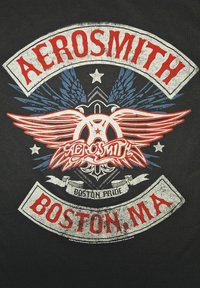 Svart T-skjorte med et sirkulært design med røde og blå vinger, teksten "AEROSMITH" og "BOSTON PRIDE" i fet skrift. Slitt tekstur.