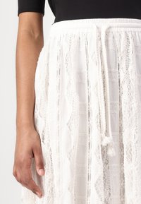 Witte kant rok met een gestrikte elastische tailleband, met een textuurpatroon en vloeibaar ontwerp, met delicate kantdetails.