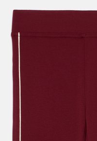 Bordó leggings sima textúrával, kontrasztos fehér oldalsávval és rugalmas derékrésszel a szoros illeszkedésért.