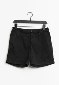 Svarta avslappnade shorts med knapp och dragkedja, hängande på en svart galge mot en vit bakgrund.