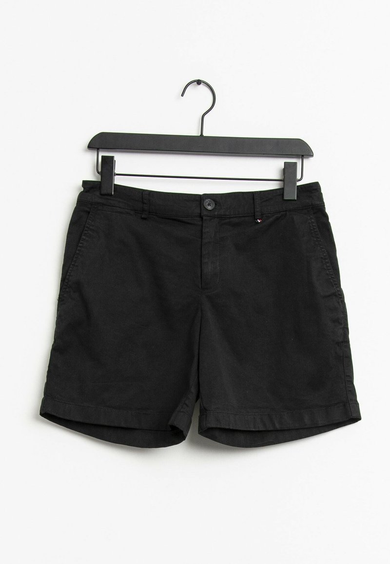 Svarta avslappnade shorts med knapp och dragkedja, hängande på en svart galge mot en vit bakgrund.