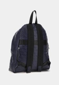 Zaino blu navy con motivo testurizzato in rilievo, doppie spalline e zip laterali, caratterizzato da una silhouette arrotondata e materiale resistente.