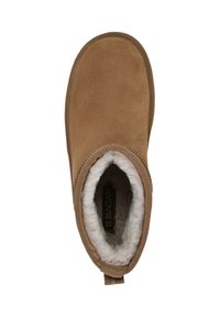 Braune Wildleder-Stiefelette mit einem weichen weißen Innenfutter, runder Spitze und einer kleinen Schlaufe an der Ferse für ein einfaches Anziehen. Niedriges Profil.