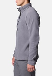 Grauer Fleece-Pullover mit hohem Kragen, Reißverschlusstasche auf der Brust und langen Ärmeln. Weicher Stoff mit Regular Fit, ideal zum Layering.