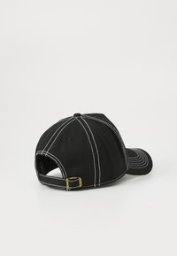 Svart baseball cap med hvit stikking, vist fra baksiden. Har justerbar stropp og rund krone. Enkel bakgrunn.