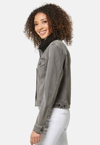 Graue Denimjacke mit schwarzem Sherpa-Kragen, Vordertaschen und Knopfdetails. Slim-Fit-Design mit klassischem Schnitt und umgeschlagenen Ärmeln.