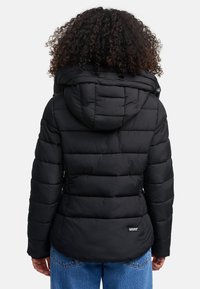Doudoune noire avec capuche, texture matelassée, poignets élastiques et une étiquette de marque en bas. Présente une coupe décontractée.