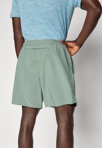 Grüne, leichte Shorts mit elastischem Bund, Seitentaschen und einer Gesäßtasche. Glattes Material mit lockerer Passform.