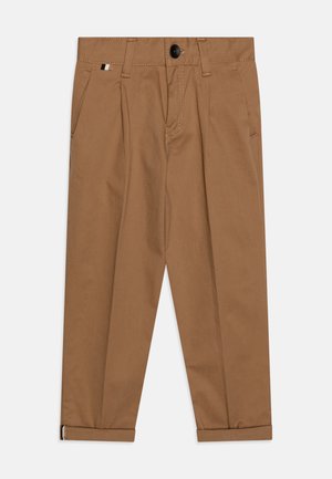Brązowe bawełniane spodnie z dwoma przednimi kieszeniami, zapięciem na guzik i podwiniętymi mankietami. Posiadają klapy oraz kontrastujący akcent po boku.