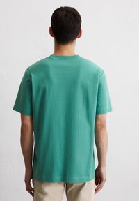 Groene katoenen t-shirt met een ronde hals, korte mouwen en een relaxed fit. Eenvoudig ontwerp zonder zichtbare patronen of versieringen.