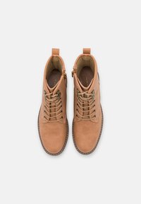 Bottes courtes en cuir tanné couleur camel, à bouts ronds, design à lacets, surface texturée et détail de couture contrastante le long de la semelle.