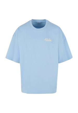 Light blue cotton t-shirt with short sleeves, oversized fit, and a small white logo on the chest. Smooth texture, round neck.