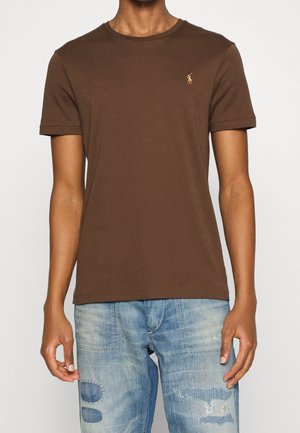 Brun bomulds t-shirt med korte ærmer, med et lille broderet logo på venstre bryst. Glat tekstur og klassisk rund hals.