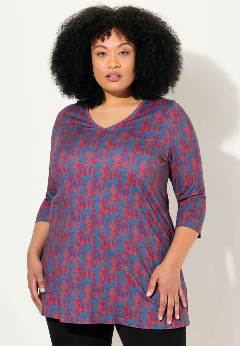 V-hals, top met driekwartmouwen in een blauw en rood abstract patroon, gemaakt van zacht materiaal met een relaxte pasvorm, eindigend op heuplengte.