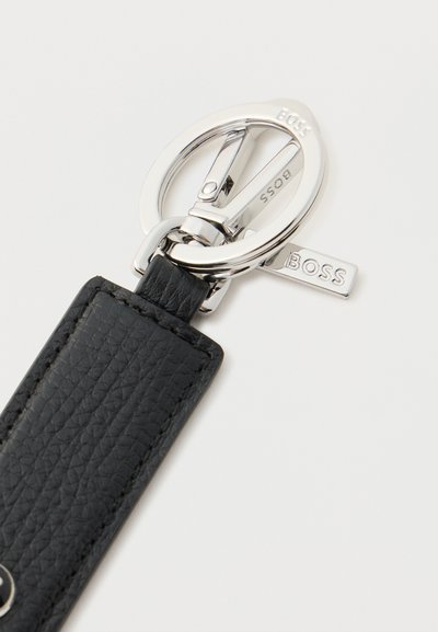 Porte-clés en cuir noir texturé avec anneau métal argenté et fermoir, comportant "BOSS" gravé sur la quincaillerie métallique.