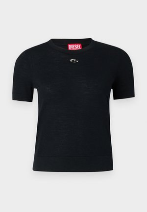 T-shirt preto de manga curta com gola redonda, feito de tecido suave, com um detalhe arredondado em prata perto do decote e uma etiqueta vermelha.