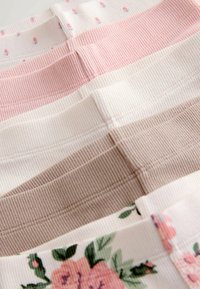 Samling av tygremsor i olika nyanser av rosa, creme och beige; innehåller blommönster och texturerad räffling.