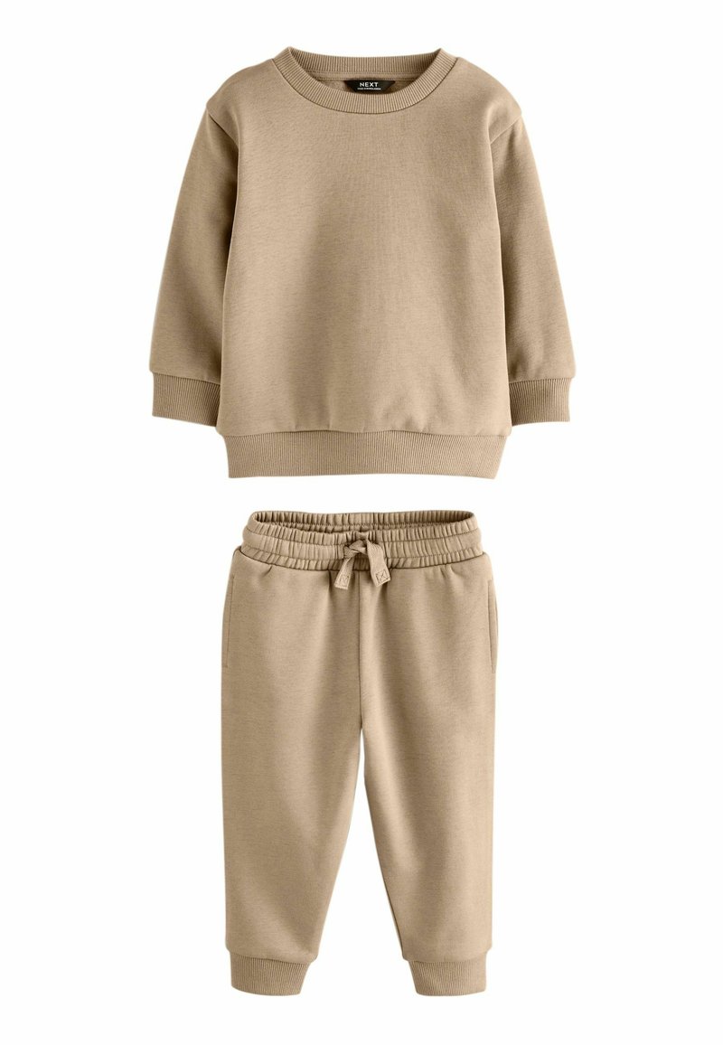 Beige Baumwollpullover mit rundem Halsausschnitt und gerippten Bündchen, kombiniert mit passenden elasticisierten Hosen mit Kordelzug und umschlägen.