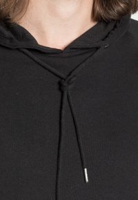 Sort hættetrøje med snøre og metaltip, rund halsudskæring og blødt, tekstureret stof. Enkel design uden pyntede detaljer.
