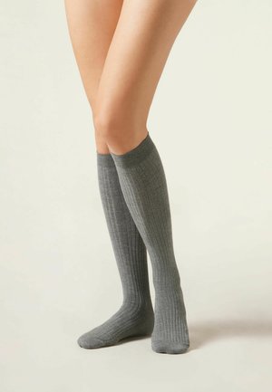 Tot de knie hoge geribde sokken in een medium grijze kleur, gemaakt van textuurstof met een nauwsluitende bovenkant en een glad voetbed voor comfort.