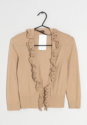 Cárdigan beige con frente abierto con volantes, mangas largas y puños y dobladillo acanalados. La tela parece suave con una textura lisa. Etiqueta adjunta.