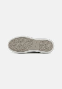Semelle de sneaker Calvin Klein avec un motif texturé en brun clair, bords en caoutchouc blanc et logo en relief. Forme incurvée pour le confort.