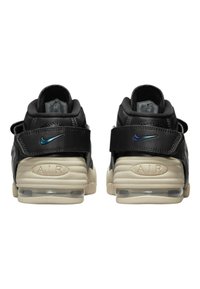 Svarta lädersneakers med en beige sula, med justerbara remmar, präglade detaljer och en blå Nike-logotyp på hälen.