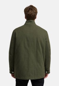 Groene, gewatteerde jas met een staande kraag, gemaakt van een gestructureerde stof en met drukknopen aan de mouwen. Achteraanzicht, zonder zichtbare merknamen of patronen.