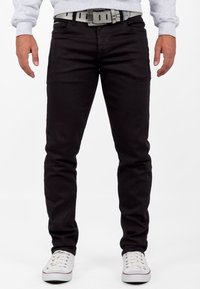 Zwarte denim jeans met een slim fit, voorzien van een grijze riem en gestyled met witte lage sneakers. Gladde textuur, klassieke 5-pocket ontwerp.