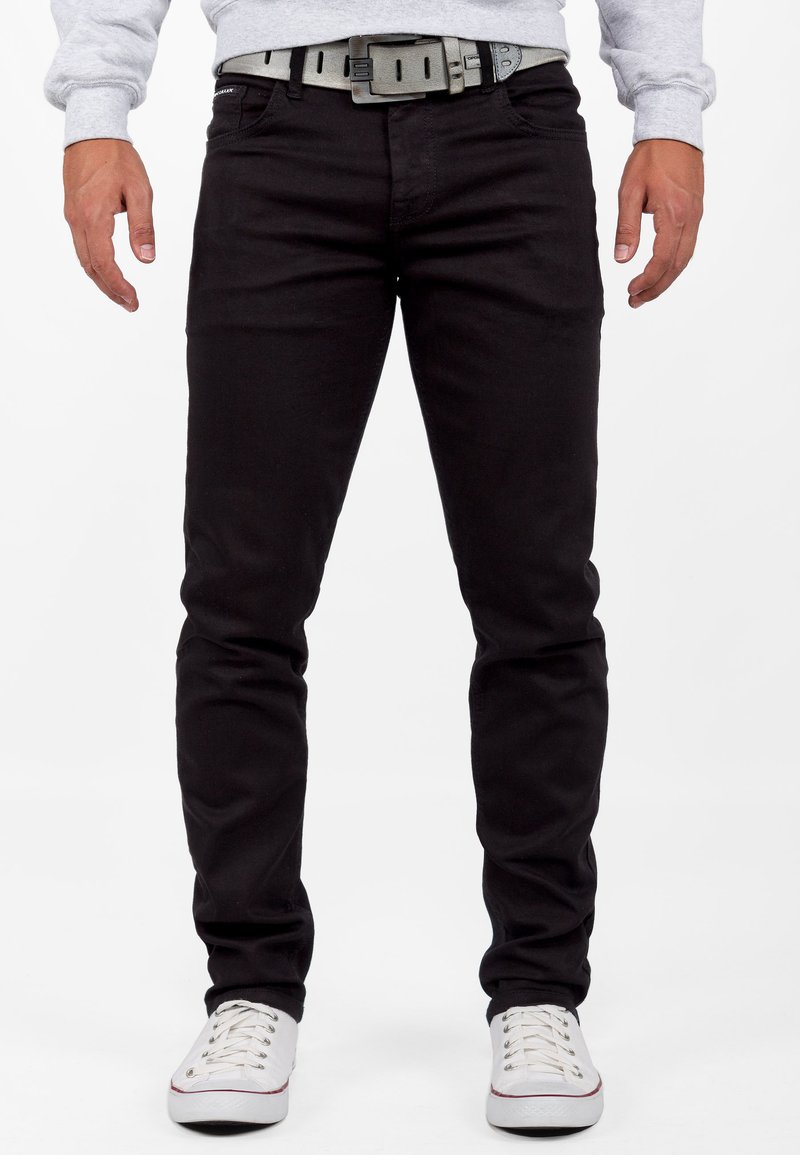 Zwarte denim jeans met een slim fit, voorzien van een grijze riem en gestyled met witte lage sneakers. Gladde textuur, klassieke 5-pocket ontwerp.
