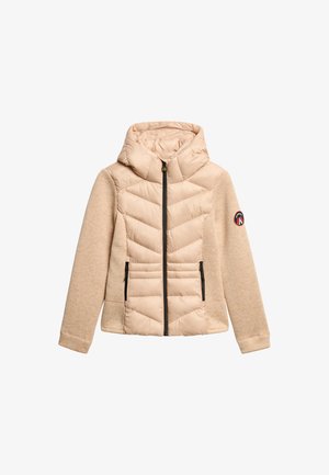 Beige jack met een puffy voorkant met chevronstiksel, gebreide mouwen, ritszakken en een capuchon. Geaccentueerd met een logo op de mouw.